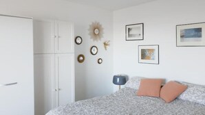 A bedroom with a bed, a wardrobe, and wall-mounted clocks. - Studio Cosy-balcon vue Mer-wifi (Berck)