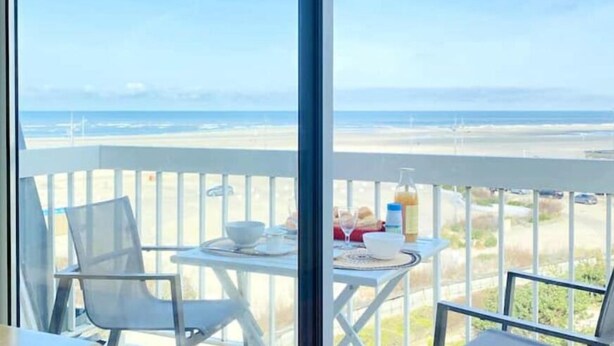 A balcony with a table set for breakfast overlooking a beach. - Studio Cosy-balcon vue Mer-wifi (Berck)