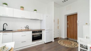 A modern kitchen with white cabinets, a built-in oven, and a refrigerator.