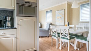 A kitchen with a built-in oven and a coffee maker, a dining area with a table and chairs, and a map on the wall.