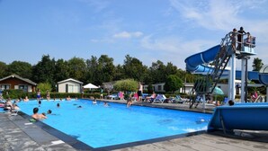 A swimming pool with a water slide and lounge chairs.
