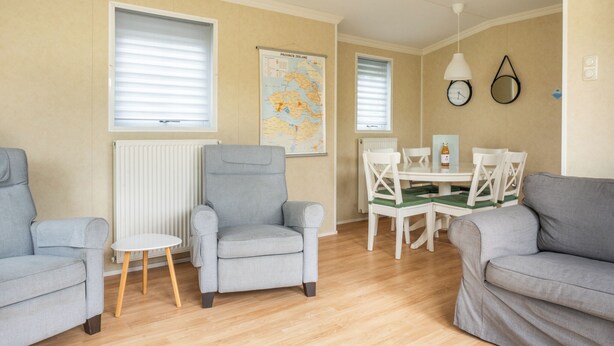 A living room with two sofas, a dining table with chairs, a radiator, and a map on the wall.
