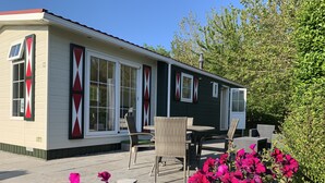 A single-story mobile home with a patio area, furnished with wicker chairs and a table.