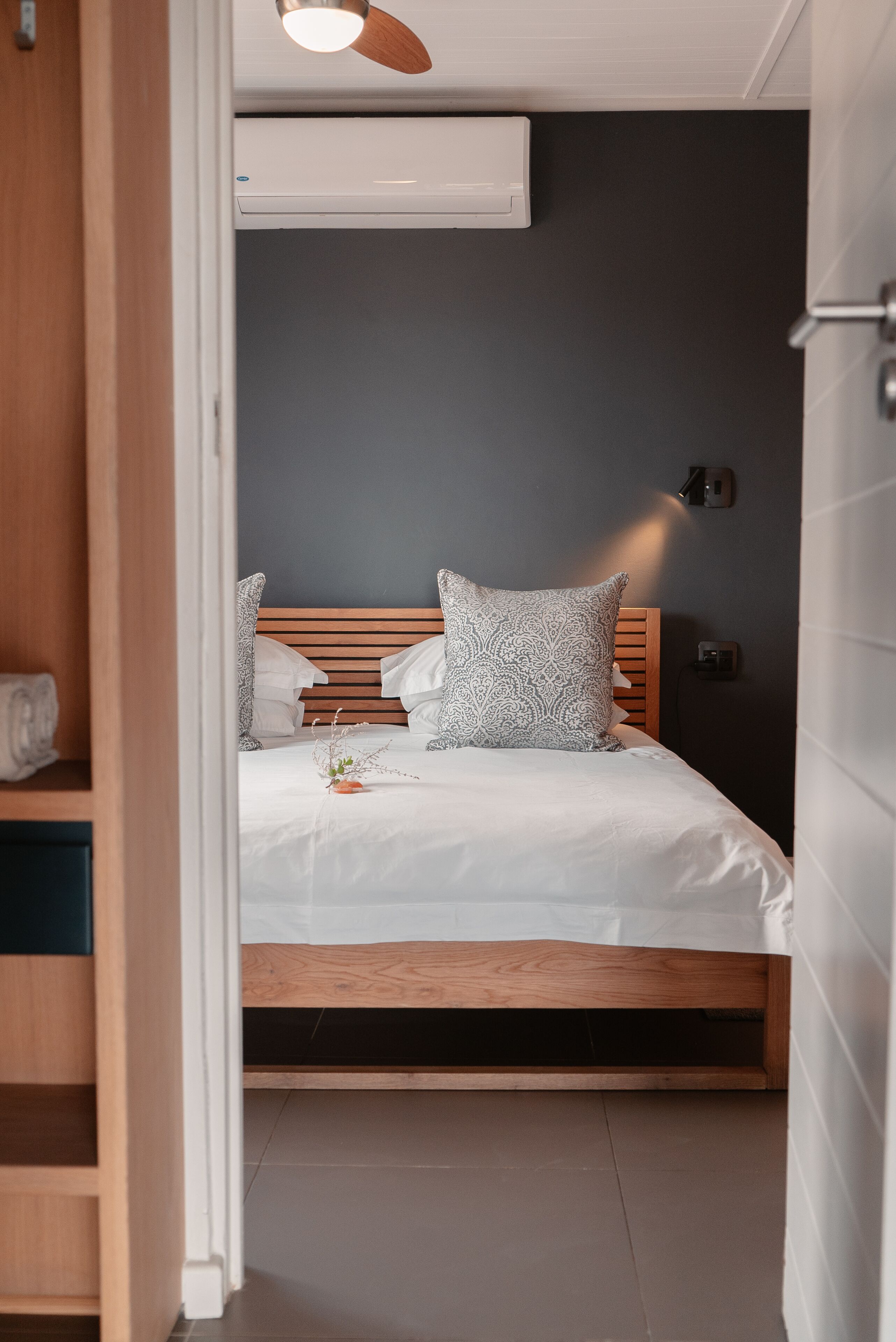 Une chambre à coucher avec un lit en bois, du linge de lit blanc et un ventilateur de plafond.
