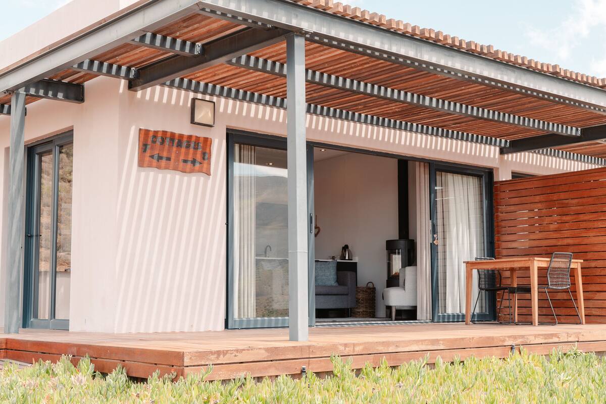 A modern house with a wooden deck, large sliding glass doors, and a covered patio area.