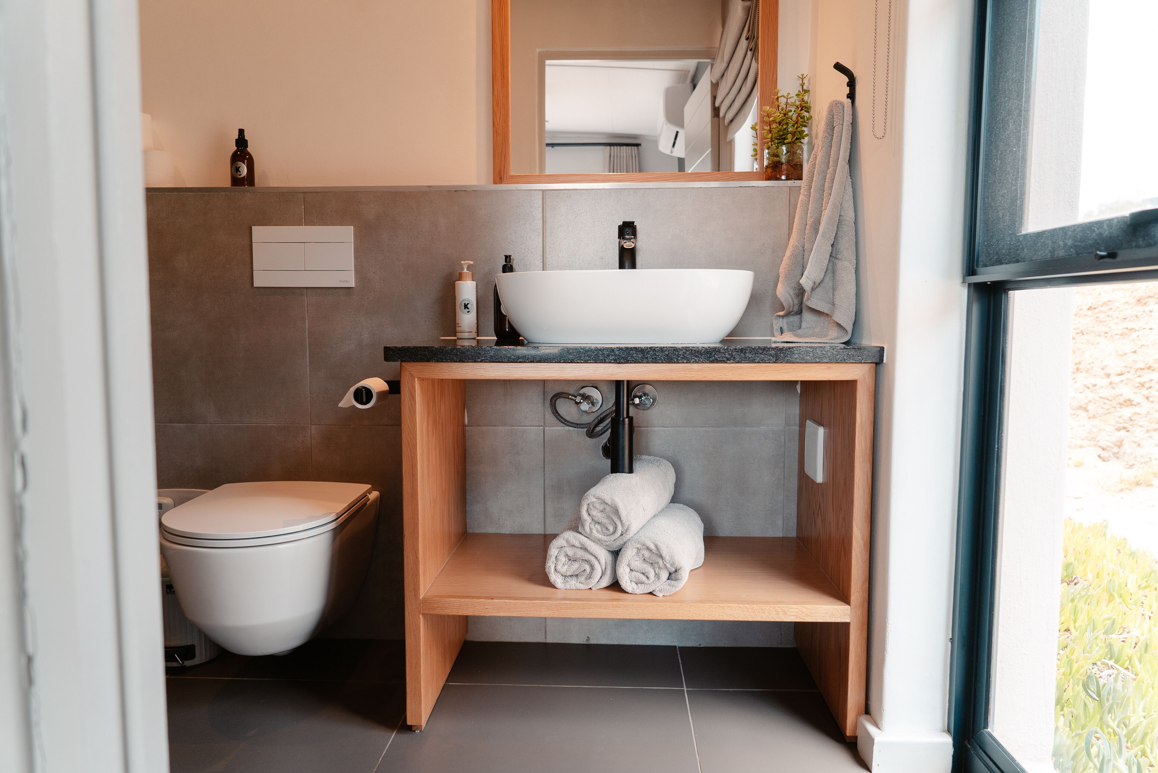 A modern bathroom with a white sink, wooden vanity, and a toilet.