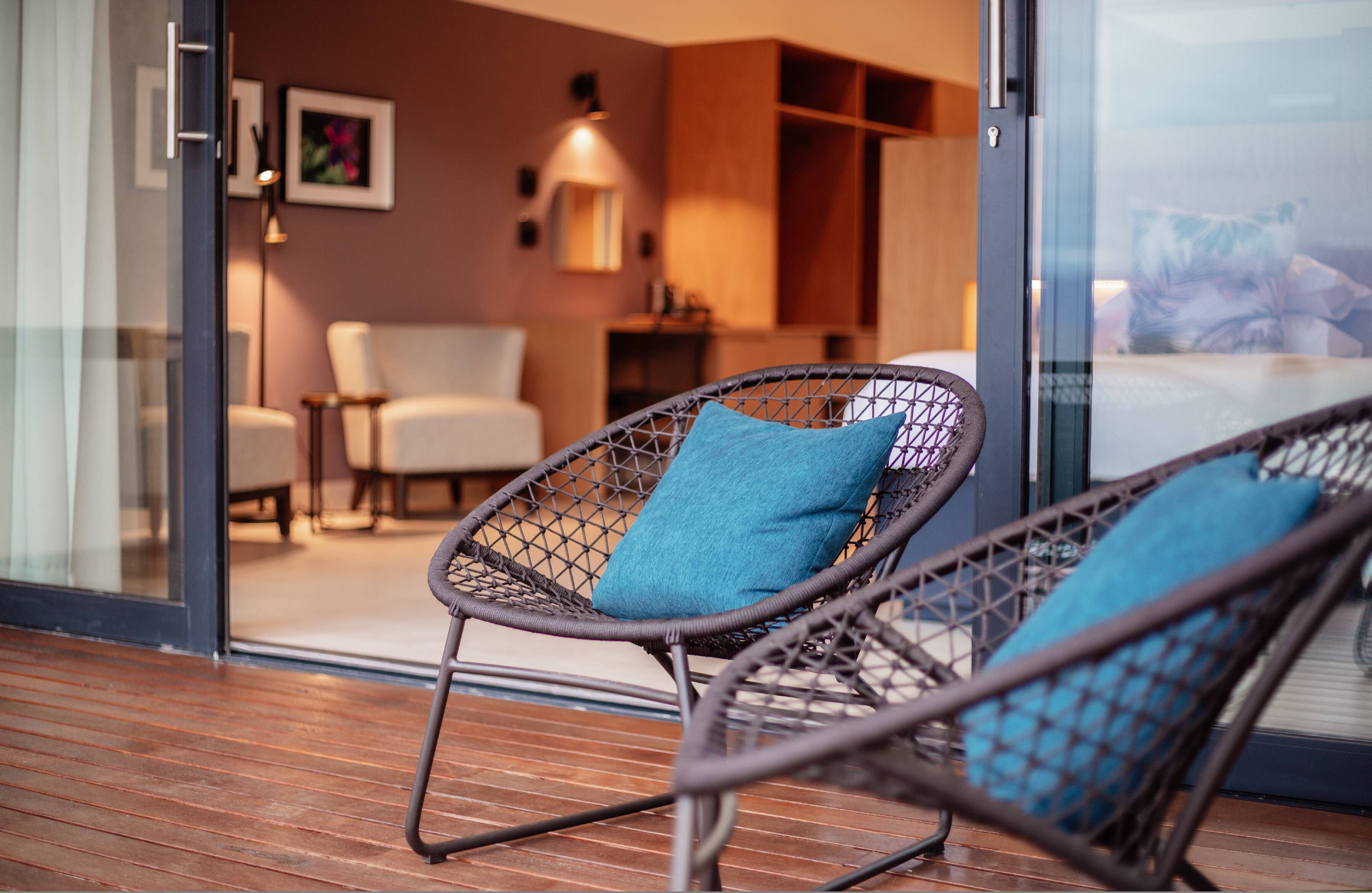 A modern outdoor seating area with wicker chairs and a glass door leading to a room.