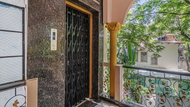 A building entrance with a black metal gate, a marble wall, and a balcony with a metal railing. - iROOMZ Hotel Ritzy Grand (Hyderabad)