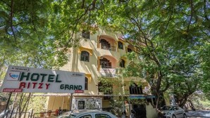 A multi-story building with a sign for "Hotel Ritzy Grand" indicating A.C. rooms and luxury stay. - iROOMZ Hotel Ritzy Grand (Hyderabad)