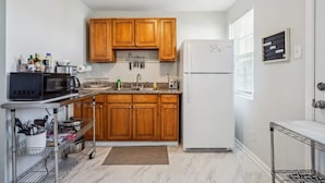 Une cuisine compacte avec des meubles en bois, un four à micro-ondes, un réfrigérateur et un petit plan de travail.