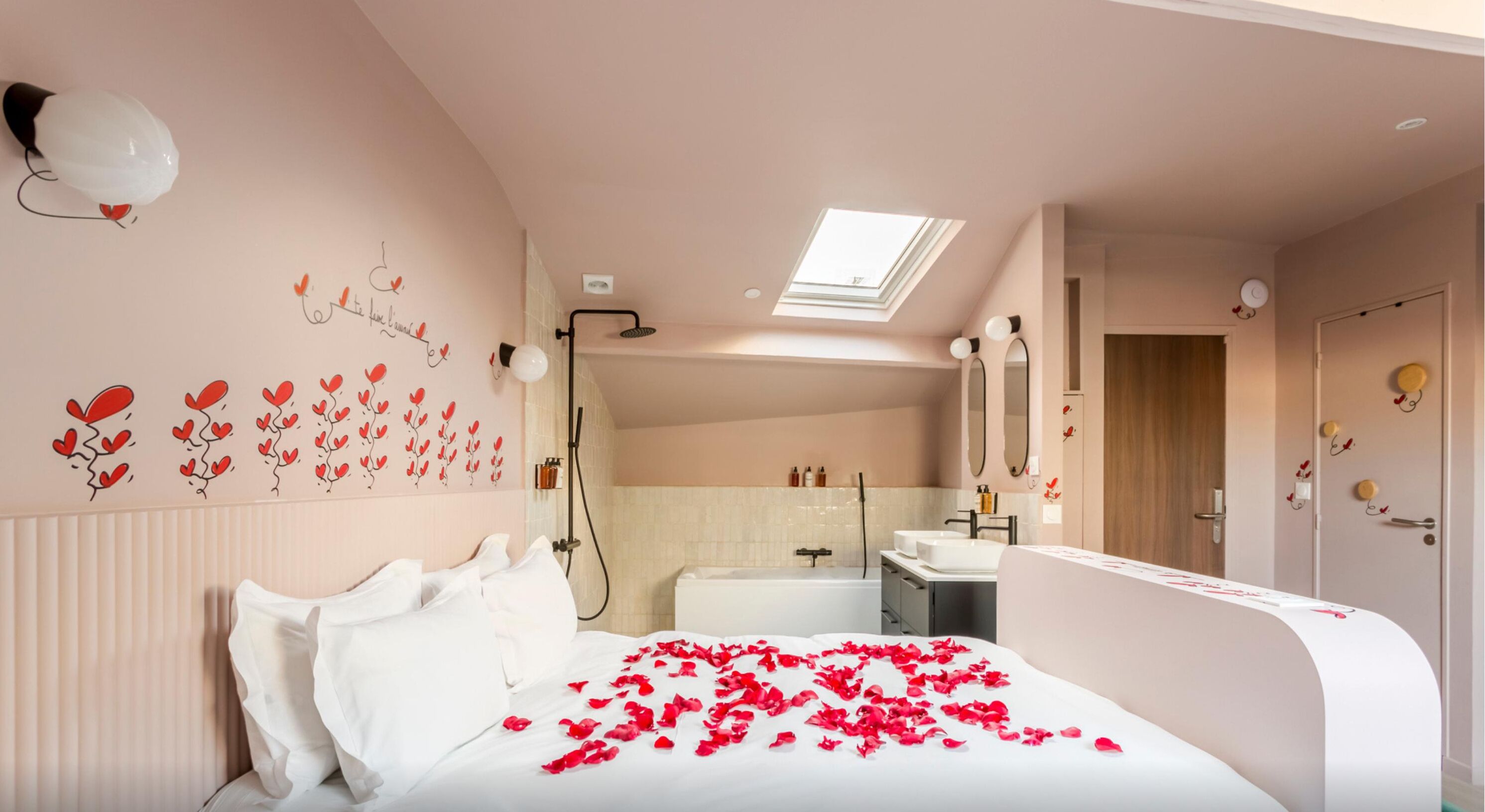 A bedroom with a bed, a skylight, a shower, and a bathroom with a sink and mirror.
