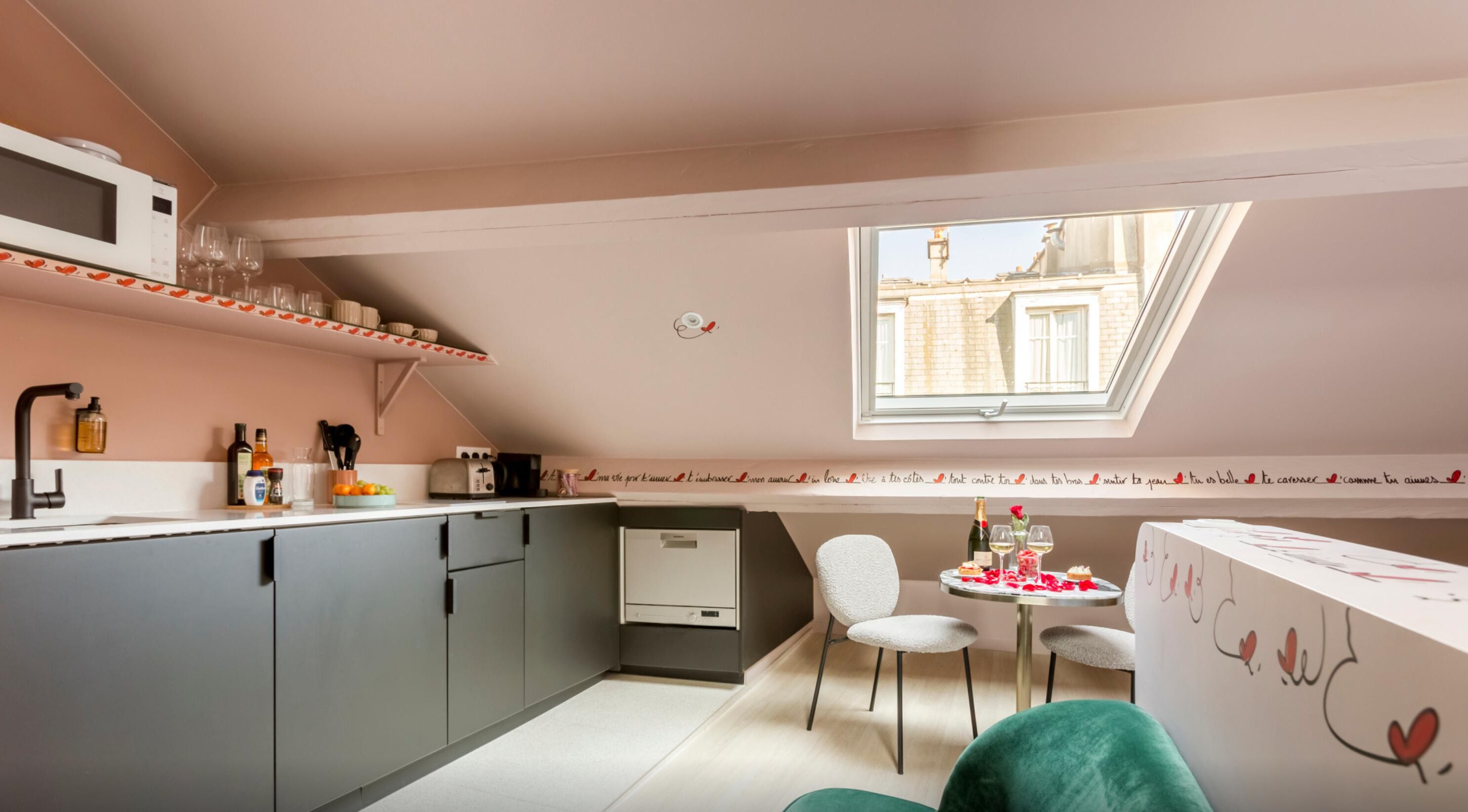 Eine kleine Küche mit Fenster, ein Essbereich mit Tisch und Stühlen sowie ein kleiner Kühlschrank.