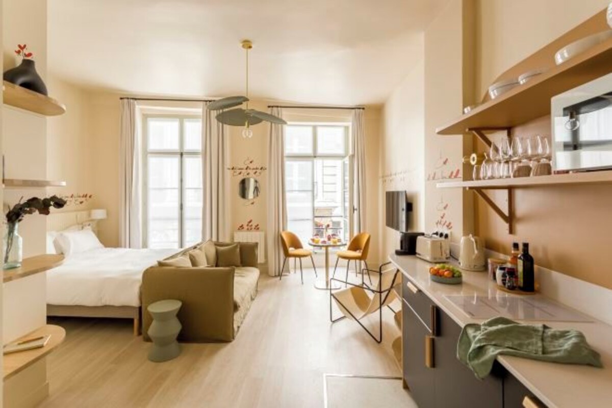 Une chambre d’hôtel moderne équipée d’un lit, d’un canapé, d’un coin repas et d’une kitchenette.