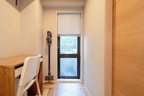 Um corredor estreito com uma porta de madeira, uma cadeira branca e uma pequena mesa.