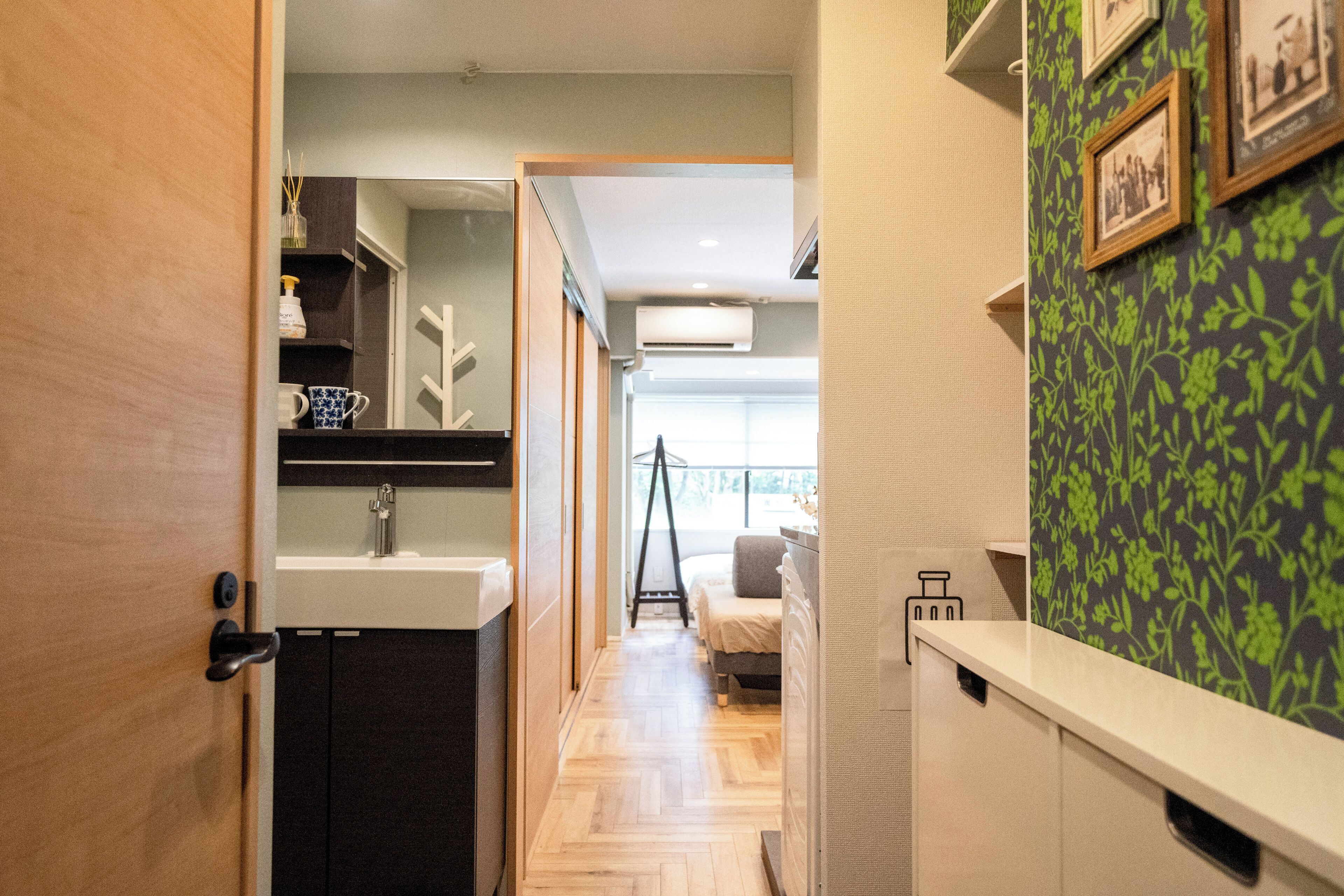 A narrow hallway with a sink, cabinets, and a bed in the distance.