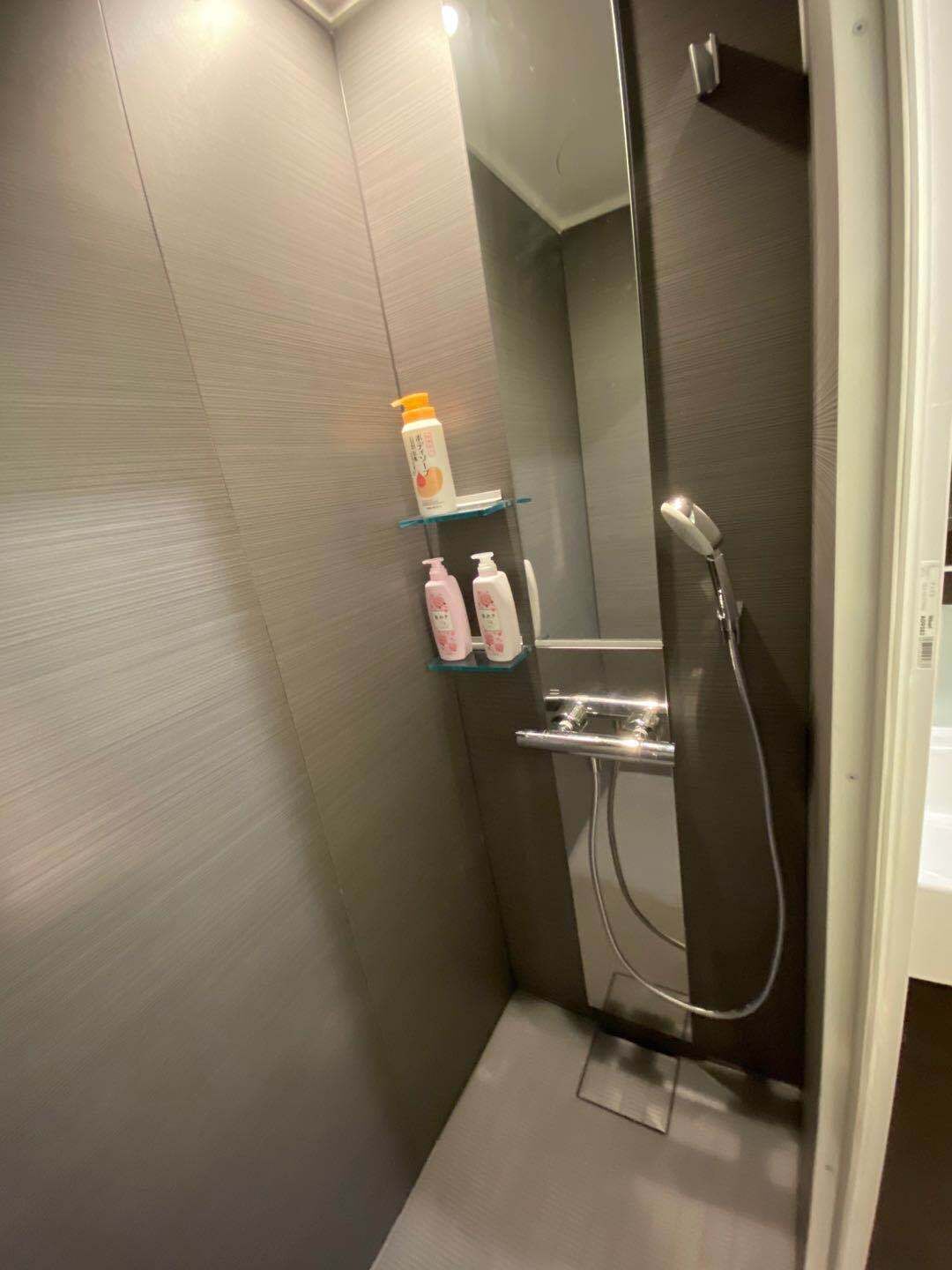 Ein modernes Badezimmer mit begehbarer Dusche, einer Glasablage für Toilettenartikel und einem Spiegel über dem Waschbecken.