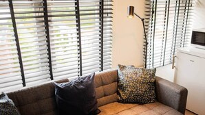 Un salon moderne avec un canapé, des coussins à motifs, une lampe sur pied et un meuble blanc.