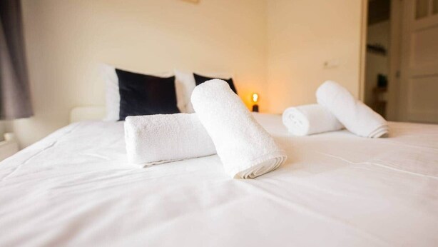 Une chambre d’hôtel avec un lit bien fait, deux oreillers et des serviettes pliées posées sur le lit.