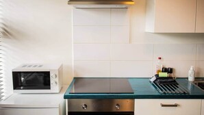 Une cuisine moderne dotée d’un plan de travail en verre, d’appareils électroménagers en acier inoxydable et de meubles blancs.