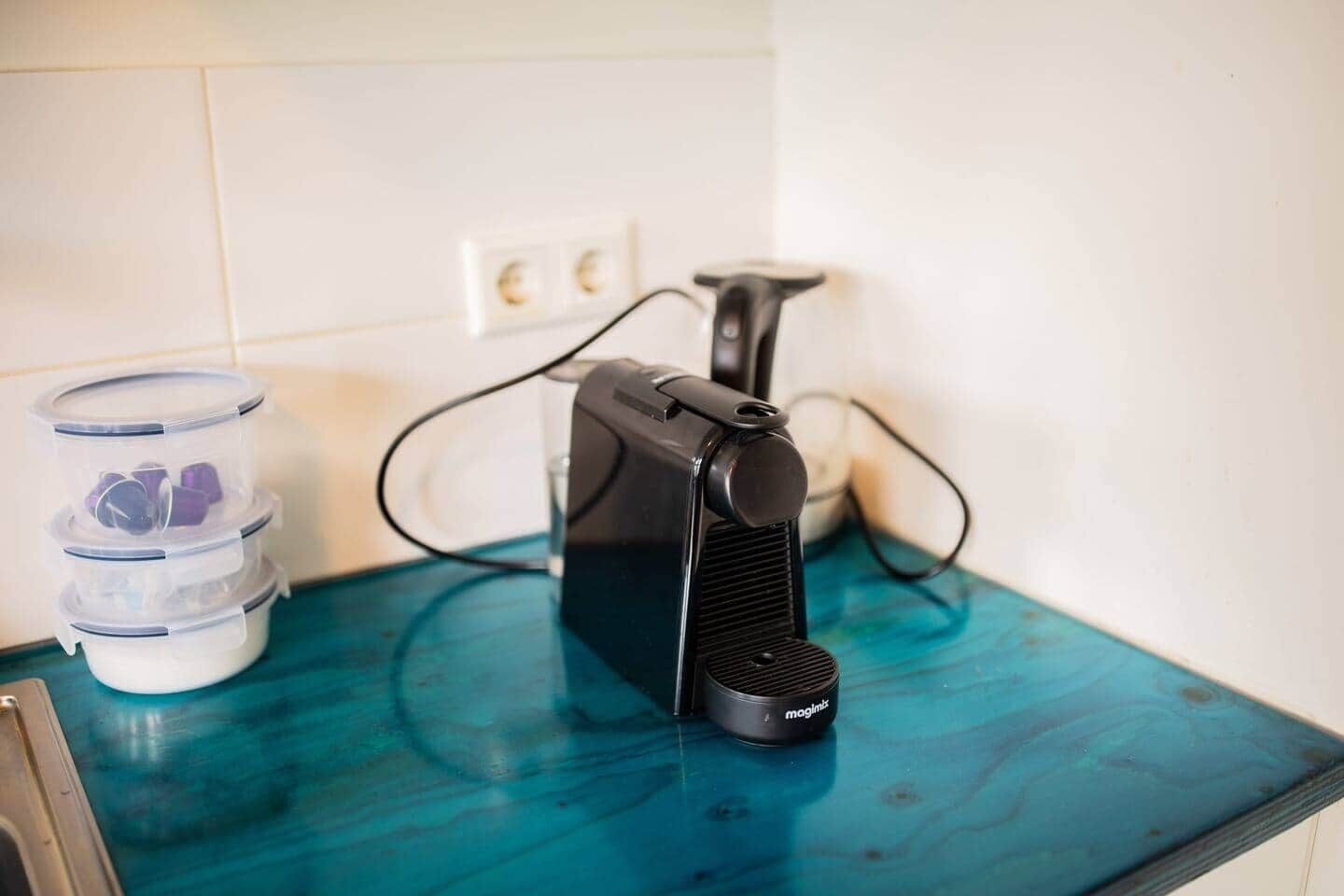 Un piano di lavoro in cucina con una macchina da caffè e contenitori impilati.