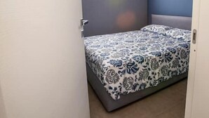 Een slaapkamer met een bed, een deur en een muur met een geometrisch lamp.
