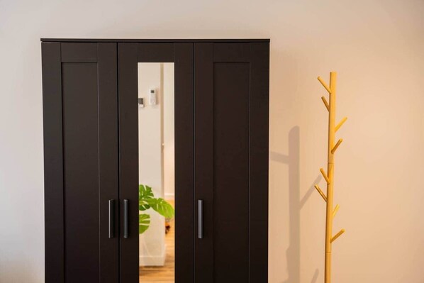 Ein Schrank mit zwei Türen, ein Kleiderhaken und im Hintergrund eine Pflanze.