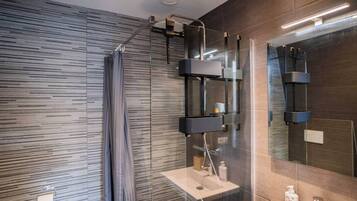 Un baño moderno con cabina de ducha de vidrio, un espejo grande y un espacio de lavamanos minimalista.