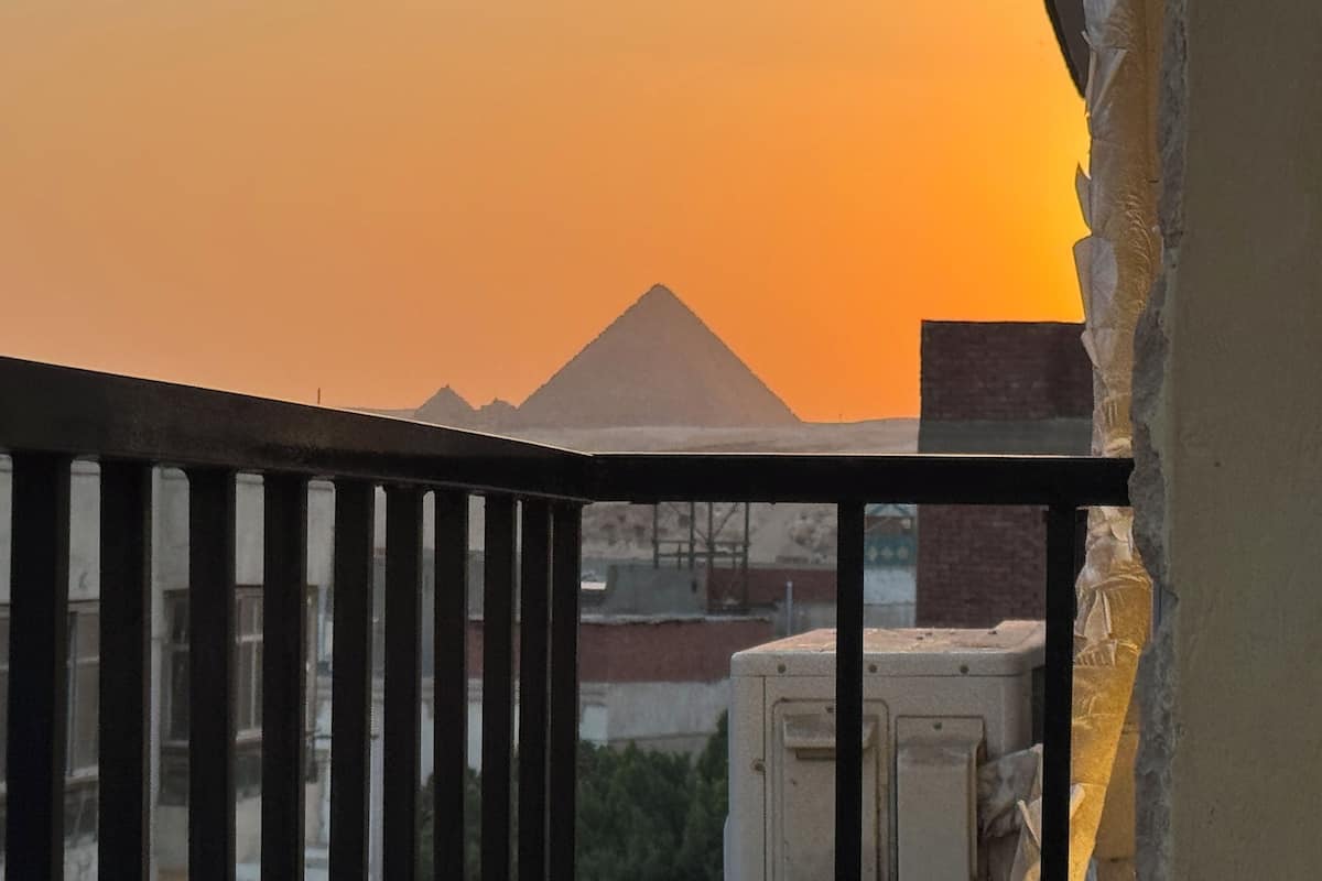 A balcony with a view of a pyramid and a sunset.