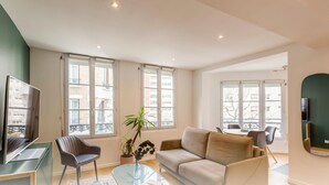 Una sala de estar moderna con un sofá, sillas, una mesa de centro y un televisor.