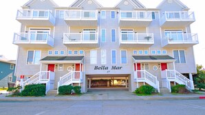 A multi-story building with balconies, a garage entrance, and a sign reading "Bella Mar".