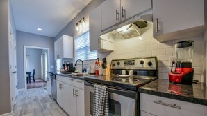 Een moderne keuken met roestvrijstalen apparatuur, witte kastjes en een granieten aanrecht.
