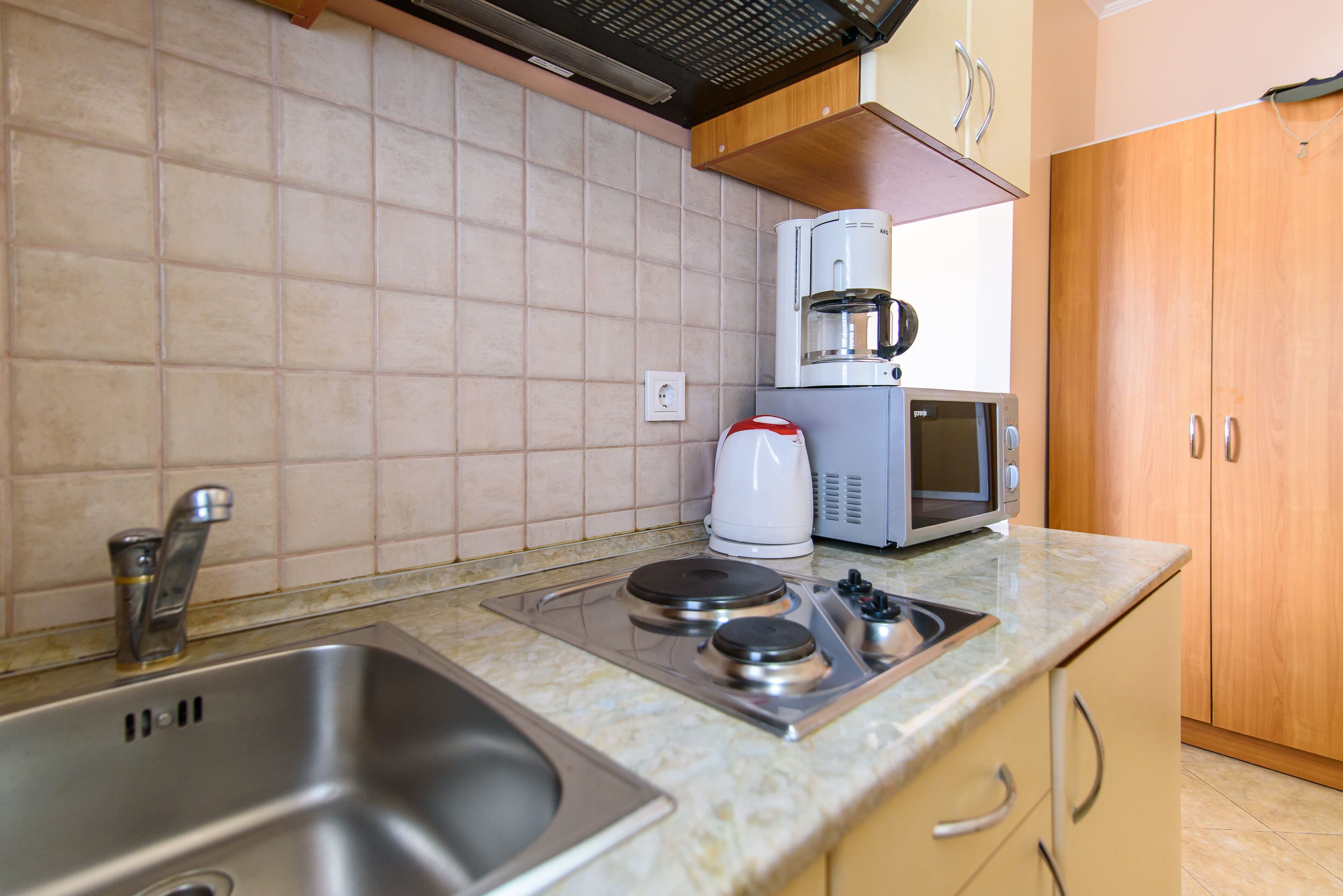 A kitchen with a sink, stove, microwave, and coffee maker.