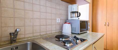 A kitchen with a sink, stove, microwave, and coffee maker.