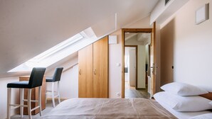 A bedroom with a bed, two chairs, a wooden wardrobe, and a skylight.
