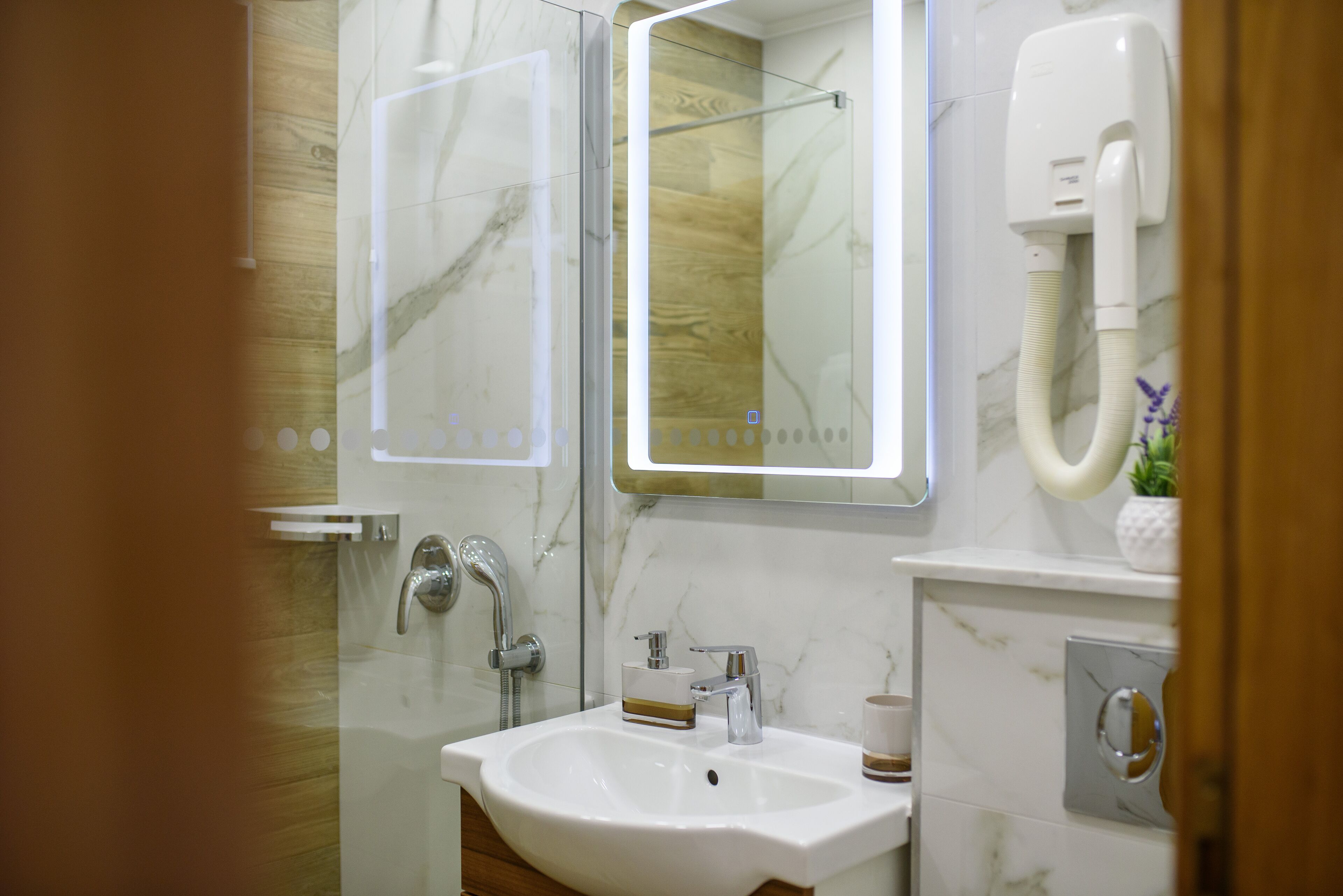 A modern bathroom with a white sink, a mirror, and a handheld showerhead.