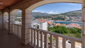 A balcony with a view of a coastal town, a mountain, and a body of water.