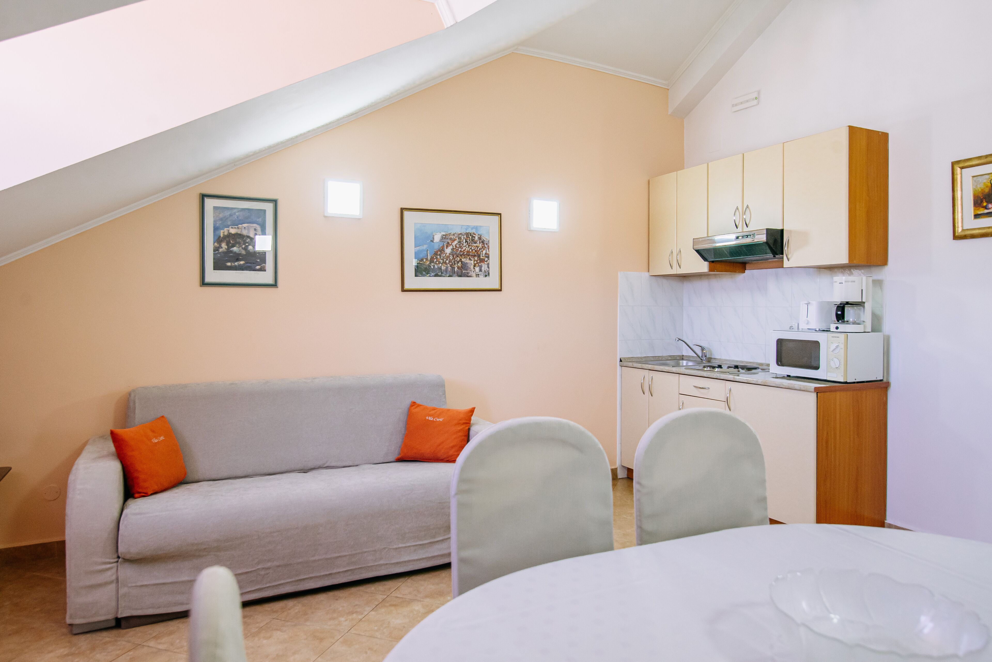 A cozy living area with a sofa, chairs, a dining table, and a kitchenette.