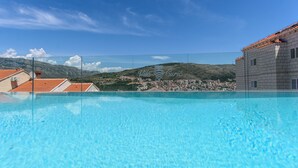 A clear blue pool with a view of a town and mountains in the background.