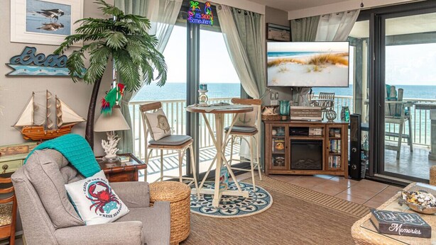 A cozy living room with a view of the sea, featuring a comfortable sofa, a small table, and a TV. - Oceanfront 3BR w/ Incredible Views+Balcony+Pools (Orange Beach)