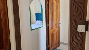A hallway with a wooden door, a mirror, and a patterned rug.