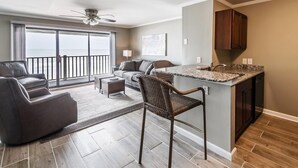 A modern living room with a sofa, a chair, and a small table. There is a balcony with a view of the ocean. - Oceanfront 2 BR Condo with a Shared Pool! Channel Marker 204 (Surfside Beach)