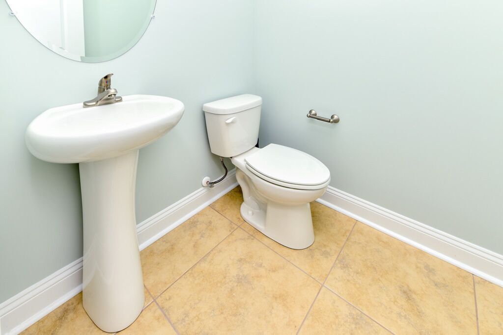 Une salle de bain avec un lavabo blanc, des toilettes et un miroir au mur.