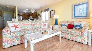 Ein Wohnzimmer mit gestreiften Sofas, einem Couchtisch und einer Küche im Hintergrund.
