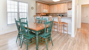A kitchen with wooden cabinets, a dining table with chairs, and a microwave. - 2nd Row 4 BR Beach House! Dream Weaver (Surfside Beach)