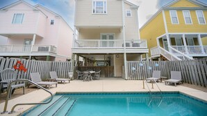 Zona residencial con piscina, patio cubierto y valla de madera.
