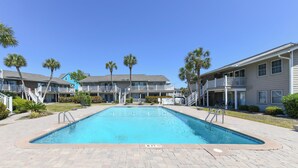 A swimming pool surrounded by a brick walkway, with palm trees and a multi-story building in the background. - 2nd Row 3 BR Condo with a Shared Pool! Floral Villas D13  (Surfside Beach)