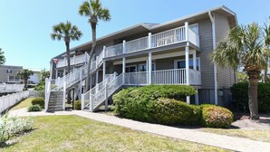 A multi-story building with a central staircase, balconies, and a well-maintained lawn. - 2nd Row 3 BR Condo with a Shared Pool! Floral Villas D13  (Surfside Beach)