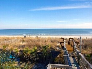 A wooden boardwalk leading to a beach with a clear view of the ocean.