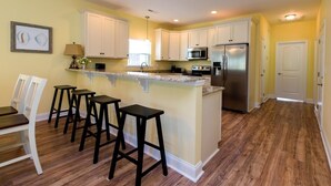 A kitchen with white cabinets, a stainless steel refrigerator, and a wooden island with bar stools.