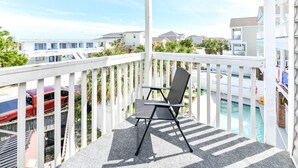 A balcony with a chair, a pool, and a view of other buildings.